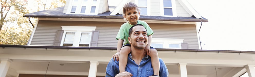 Man and child in front of house