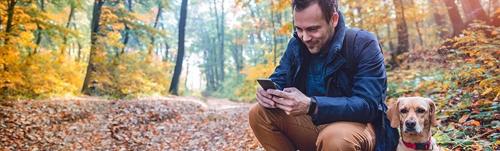 Man looking at phone with a dog