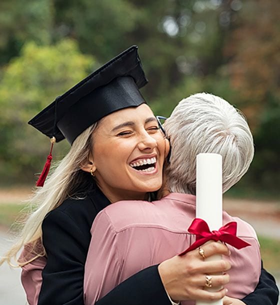 Graduate hugging woman