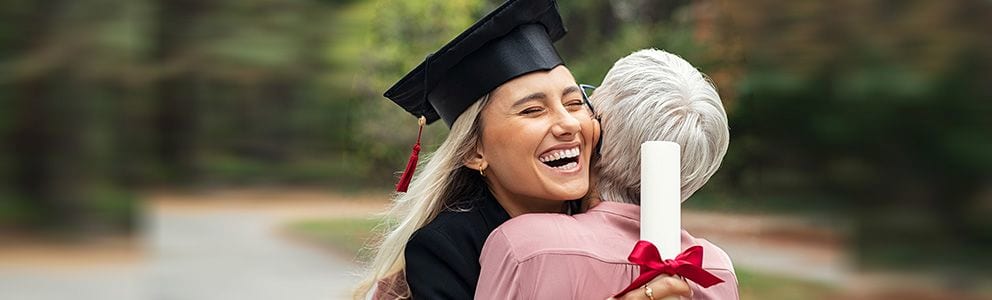 Graduate hugging woman