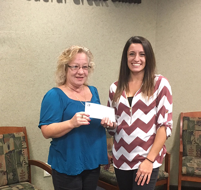 TFCU Member Service representative Deanna Coburn presenting TFCU's donation to Laura Muniz from the Port Henry Fire Department Women's Auxiliary, for their annual Toy Drive.