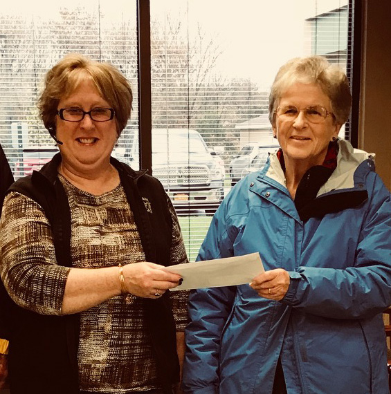 TFCU receptionist Debbie Yaw presenting TFCU's donation to Margaret Beuerlein for the TrailNorth Food Pantry